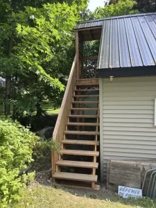 Escalier extérieur en bois fraîchement installé menant à un grenier rénové, réalisé par Construction MFA.