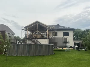 Vue sur un chantier de construction avec l'installation d'un toit permanent sur un patio par Construction MFA, montrant l'expertise en charpenterie et menuiserie.